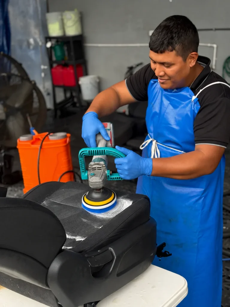 Operador de Listo y Limpio cepillando la tapicería de un asiento de auto con equipo rotativo.